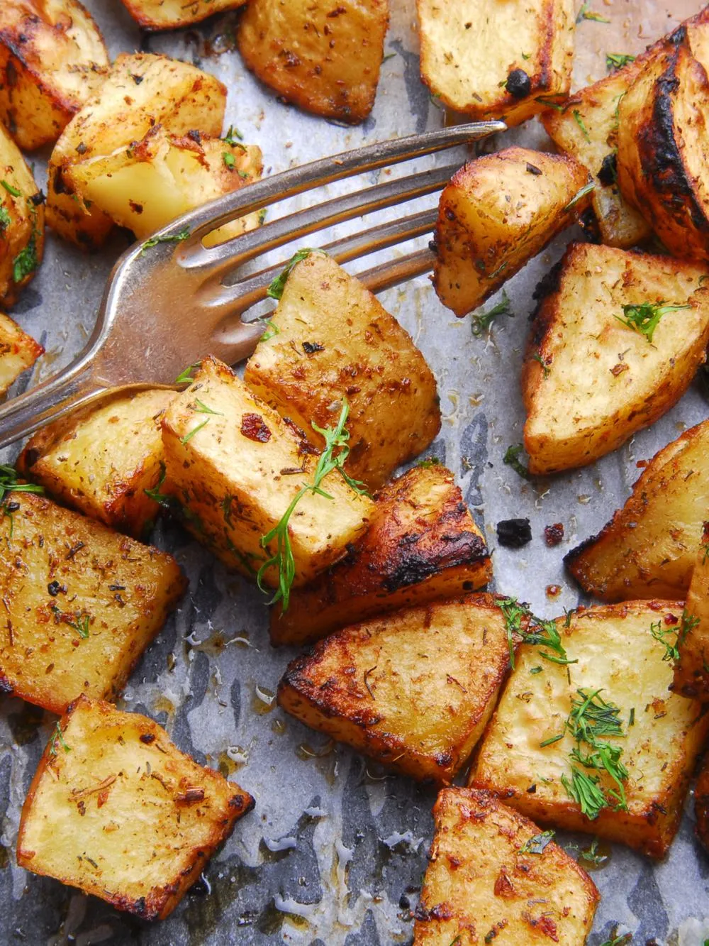 turkish potatoes on a parchment lined dish topped with fresh herbs and a silver fork